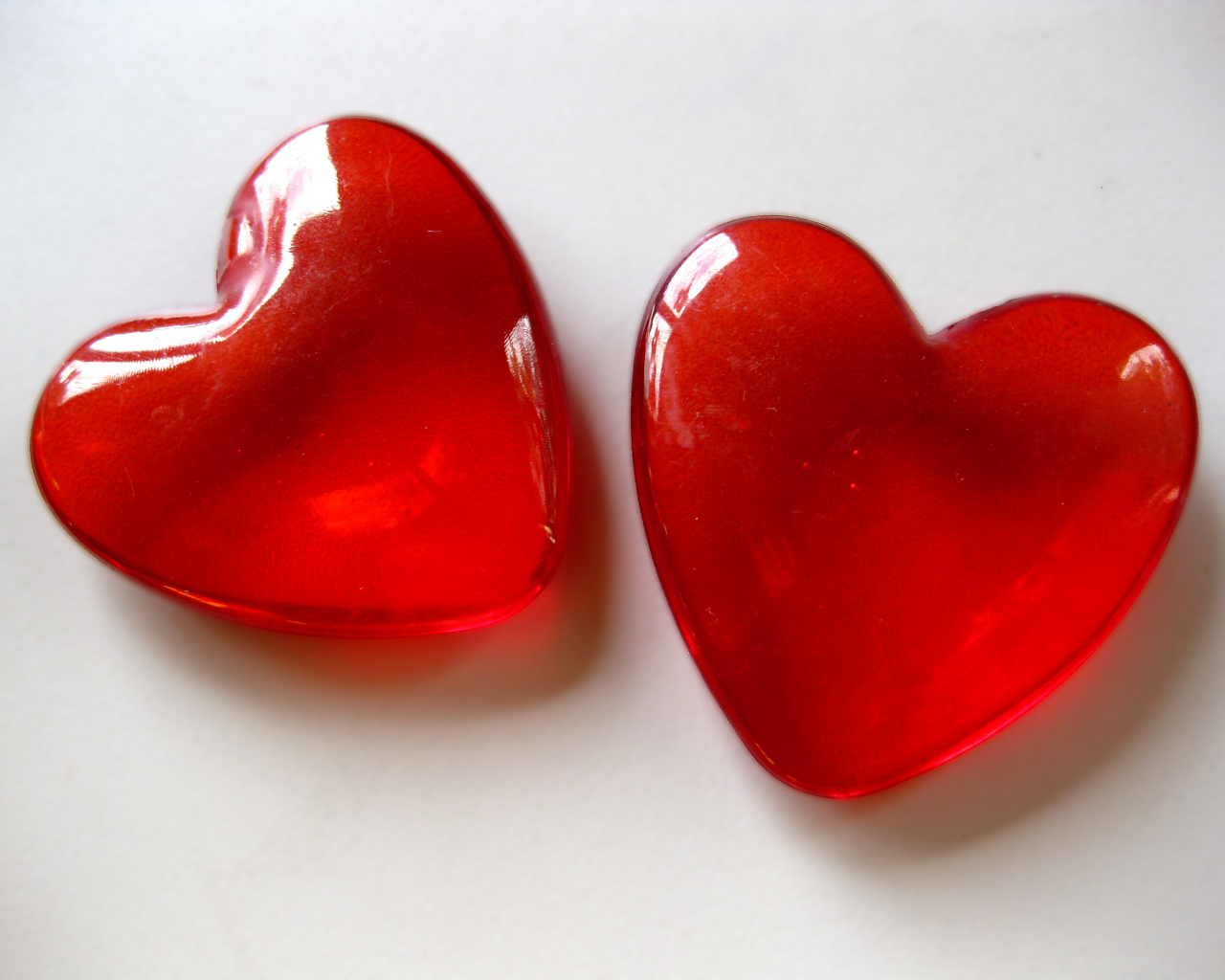 Два красных стеклянных сердца на сером фоне