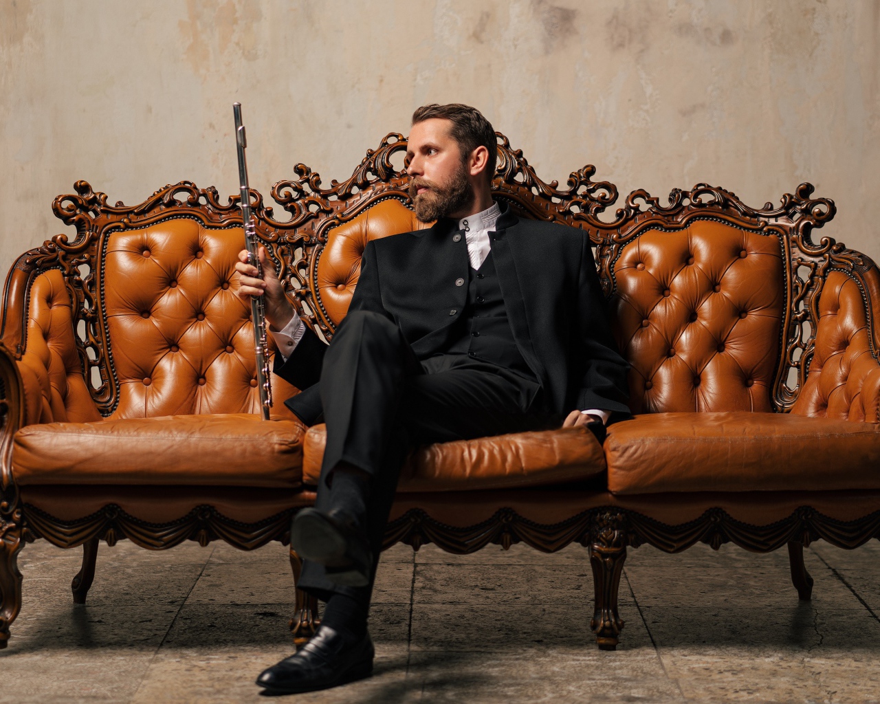 Солидный мужчина в костюме сидит на диване