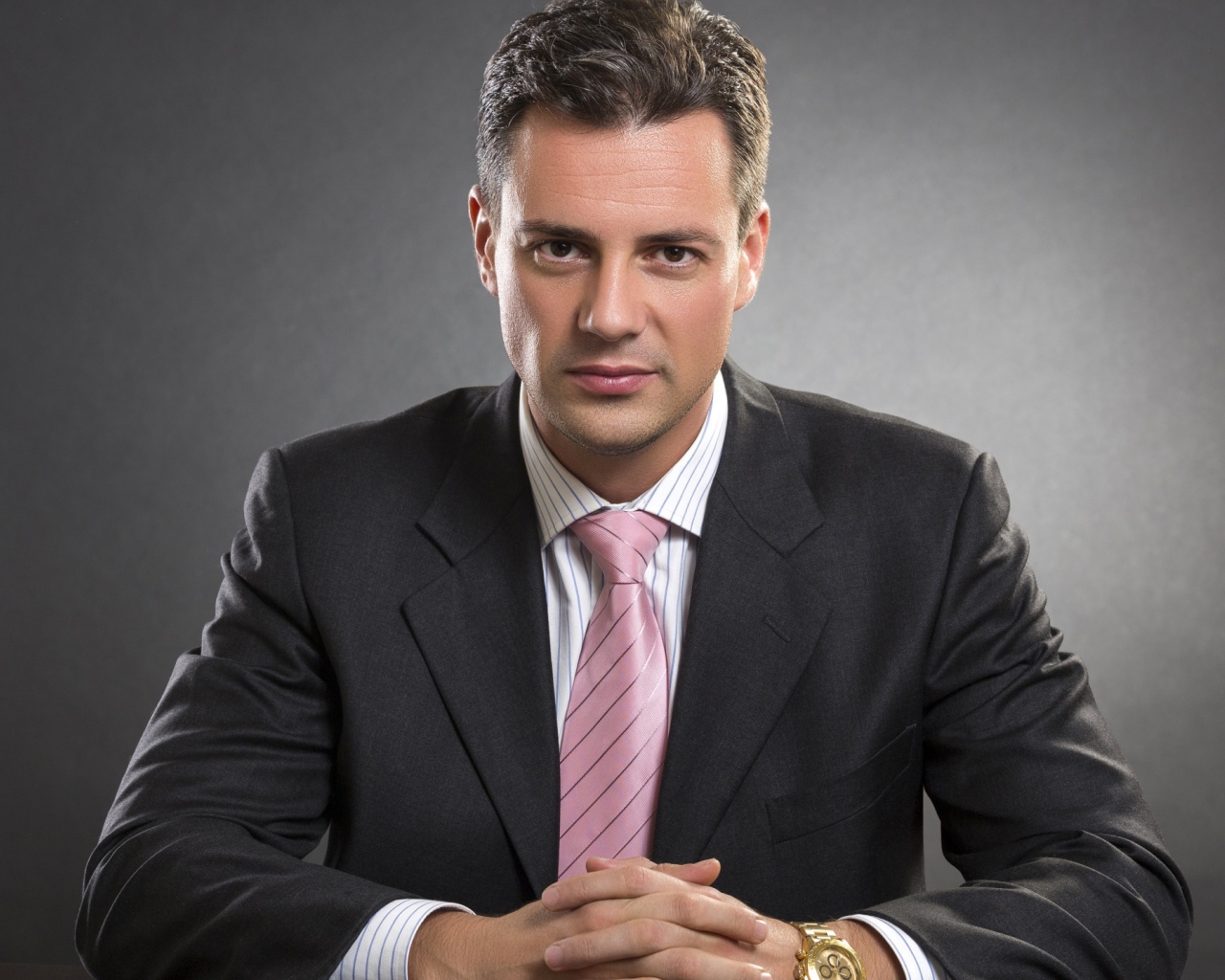 Деловой мужчина в костюме на фоне серой стены 