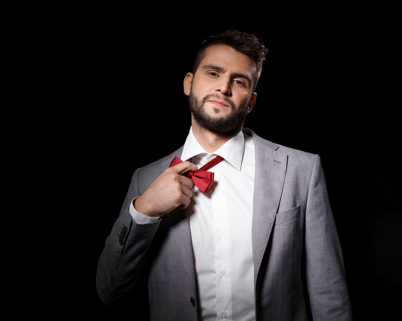 Красивый мужчина в сером пиджаке на черном фоне