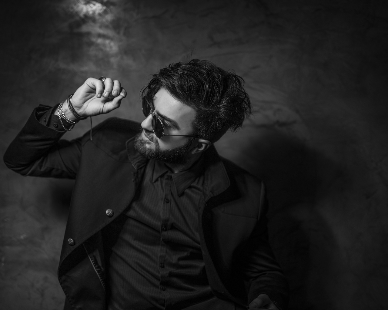 Мужчина в черном костюме на фоне стены