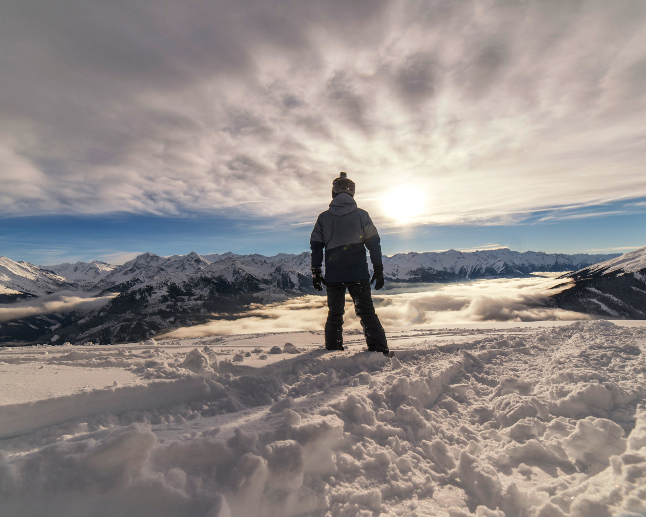 Человек в заснеженных горах в лучах солнца