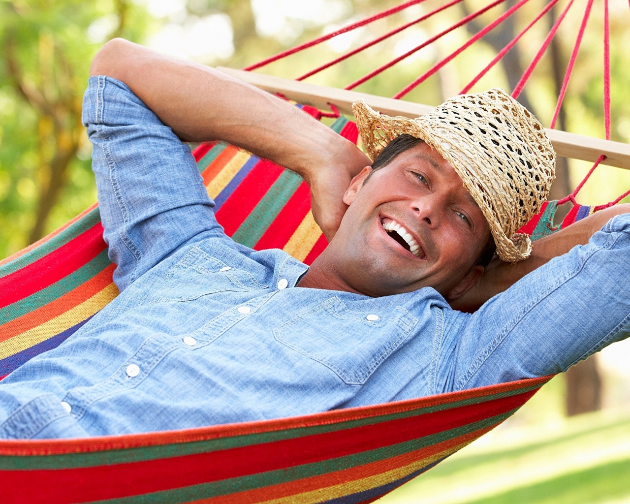 Улыбающийся мужчина спит в гамаке