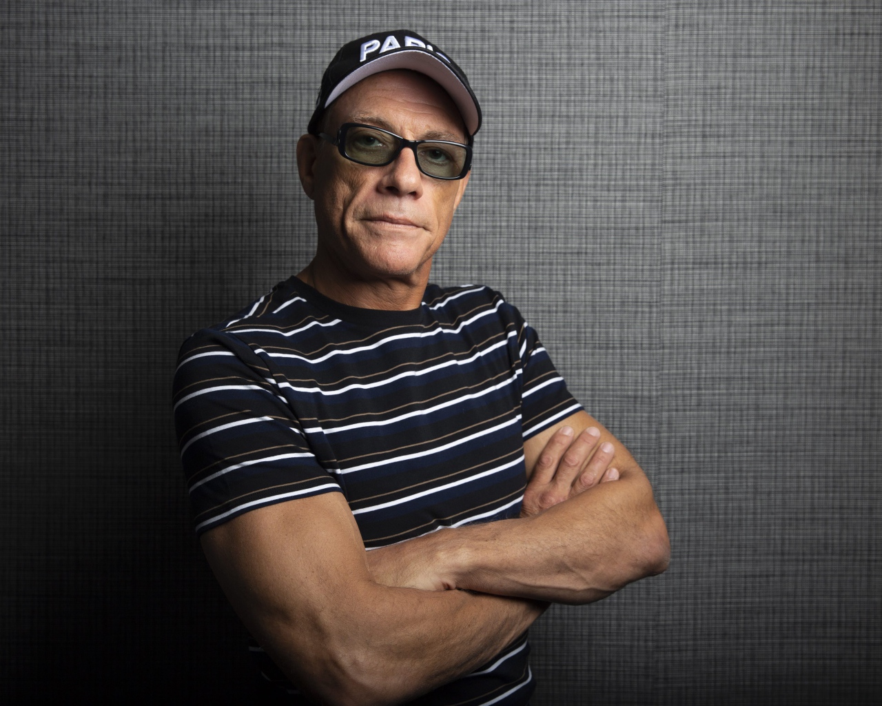 Популярный актер Жан-Клод Ван Дамм в кепке у стены