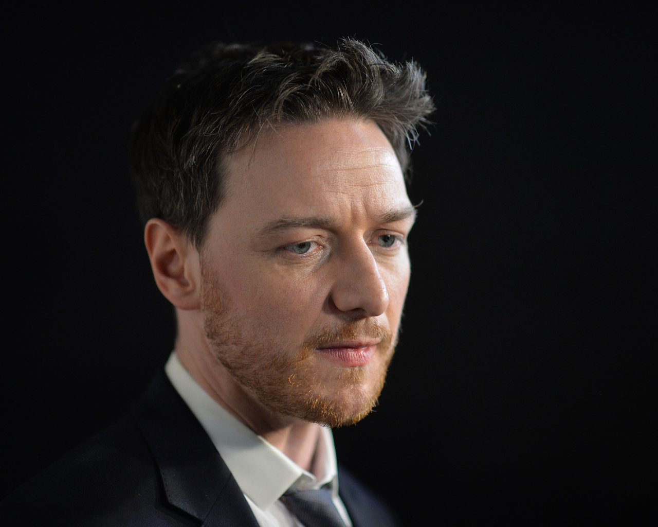 Грустный актер Джеймс МакЭвой на черном фоне