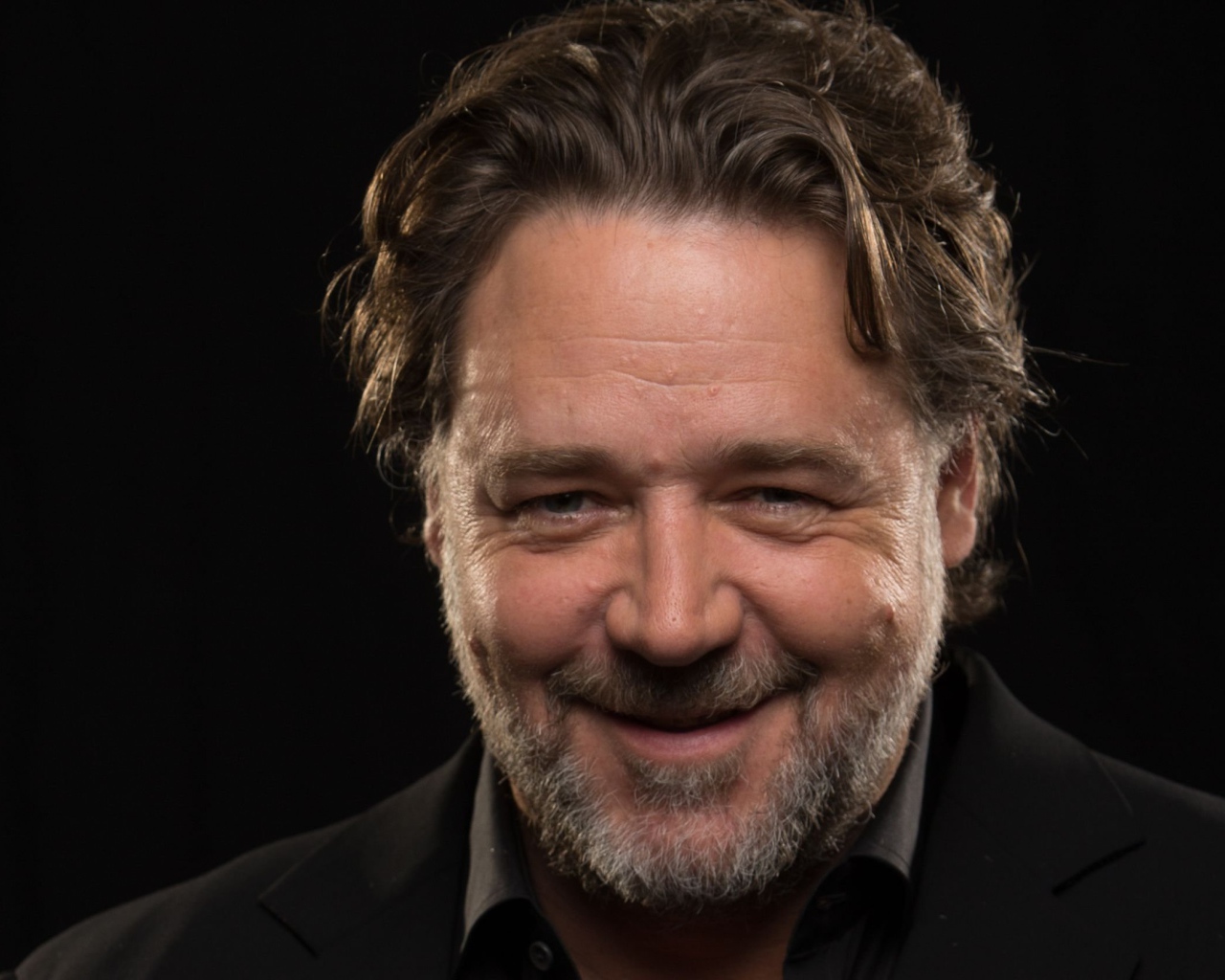 Улыбающийся Рассел Кроу на черном фоне