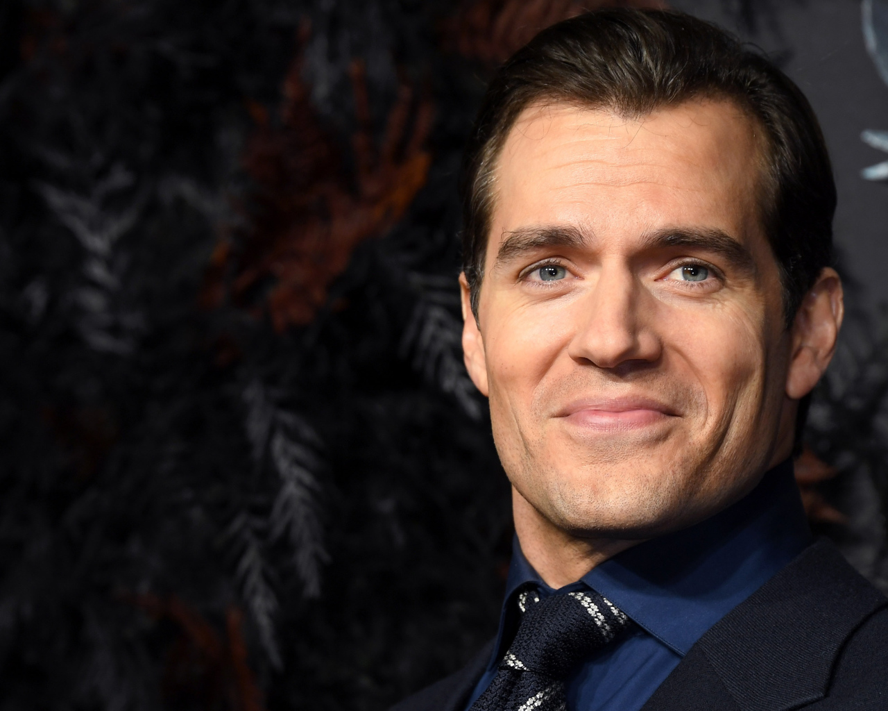 Улыбающийся актер Генри Кавилл в костюме