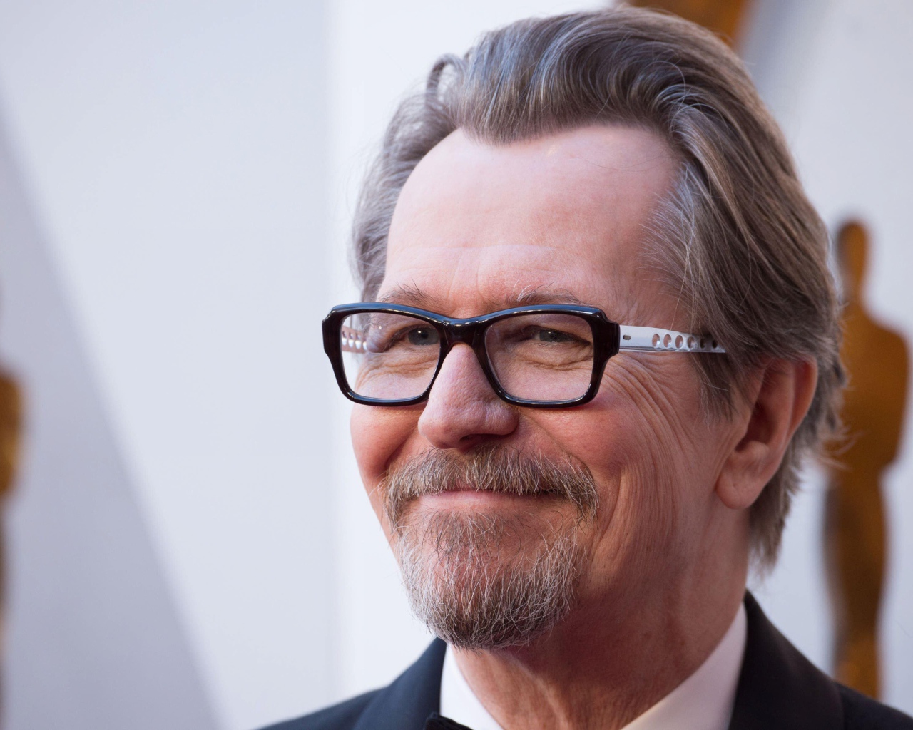 Улыбающийся мужчина, актер Гари Олдман в очках