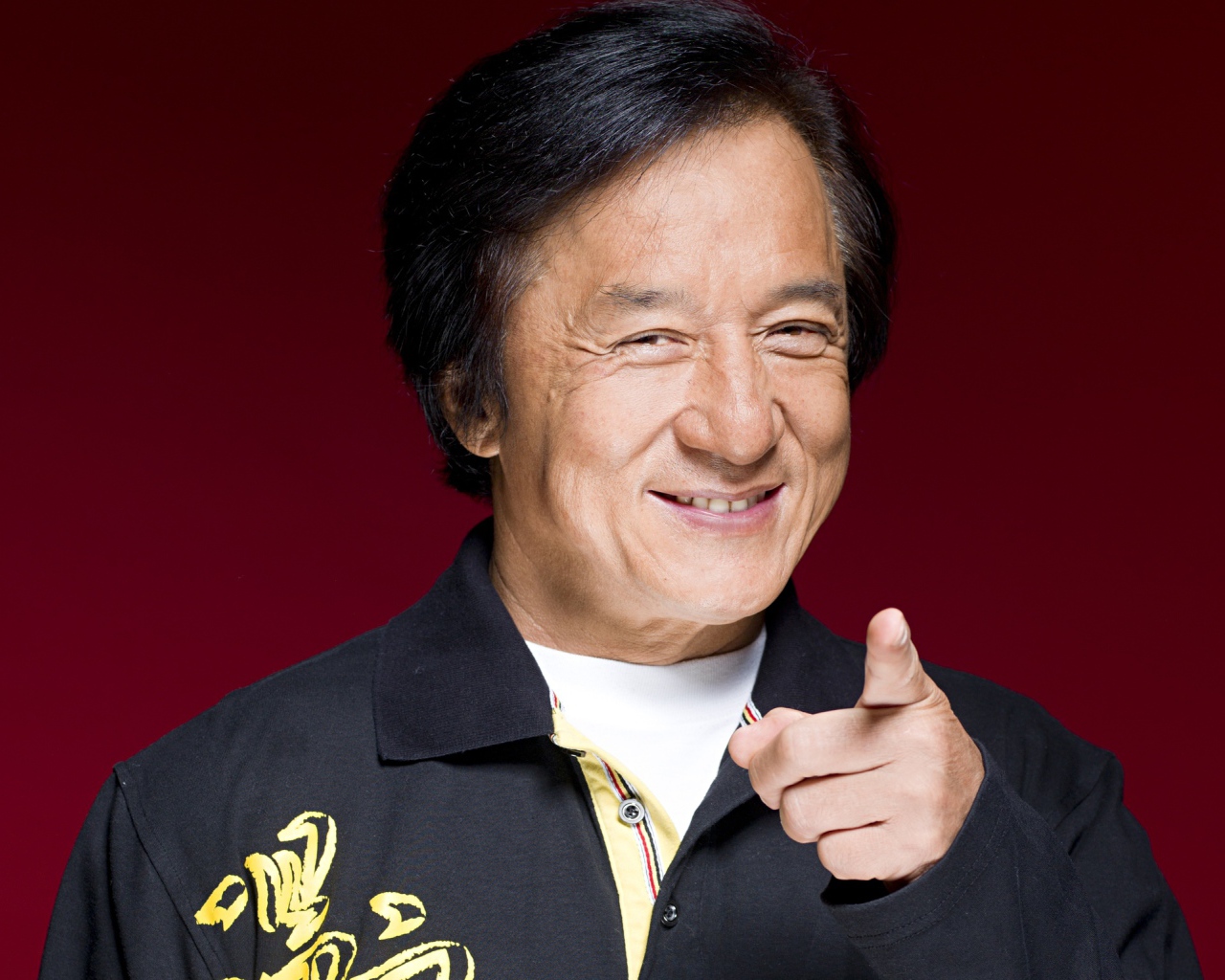 Улыбающийся мужчина, актер Джеки Чан на красном фоне