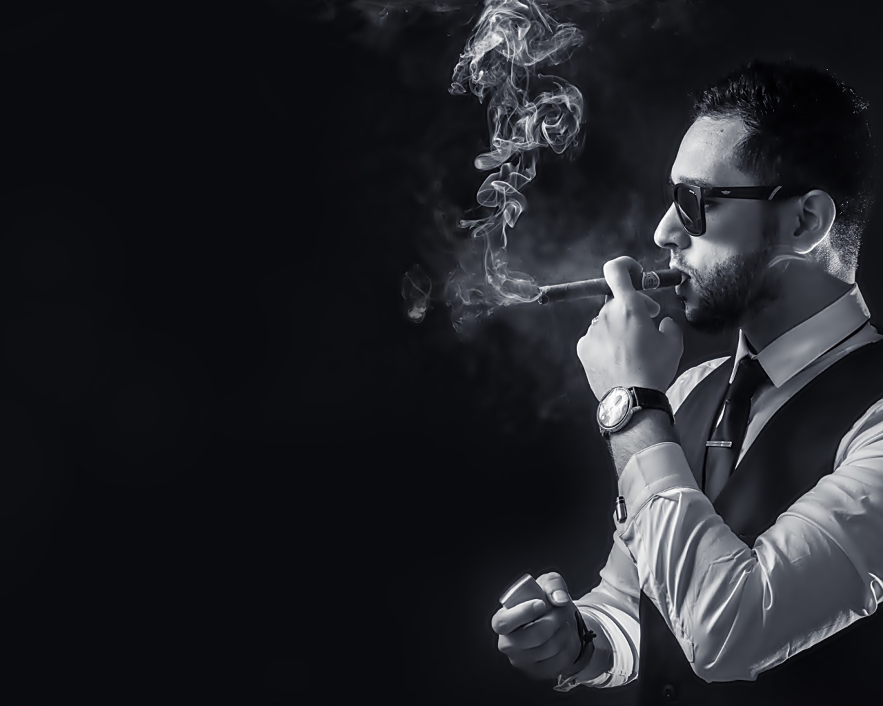 Мужчина с сигарой в руке на черном фоне 