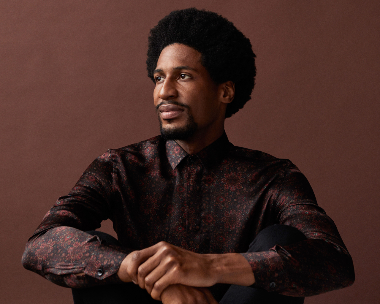 Музыкант Джонатан Батисте на коричневом фоне