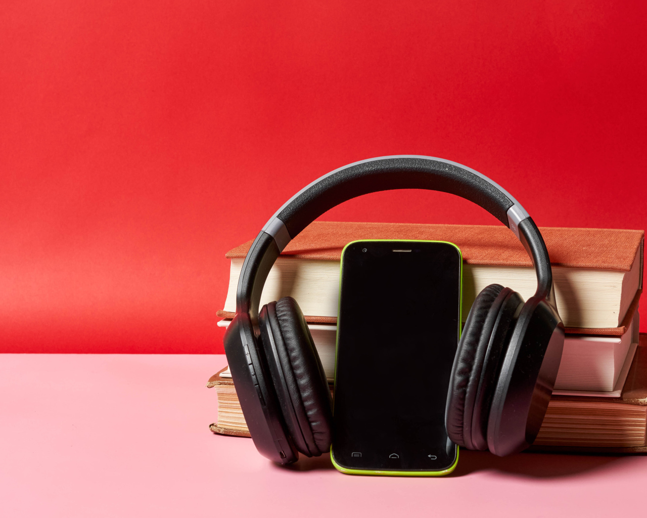 Смартфон, наушники и книги на красном фоне
