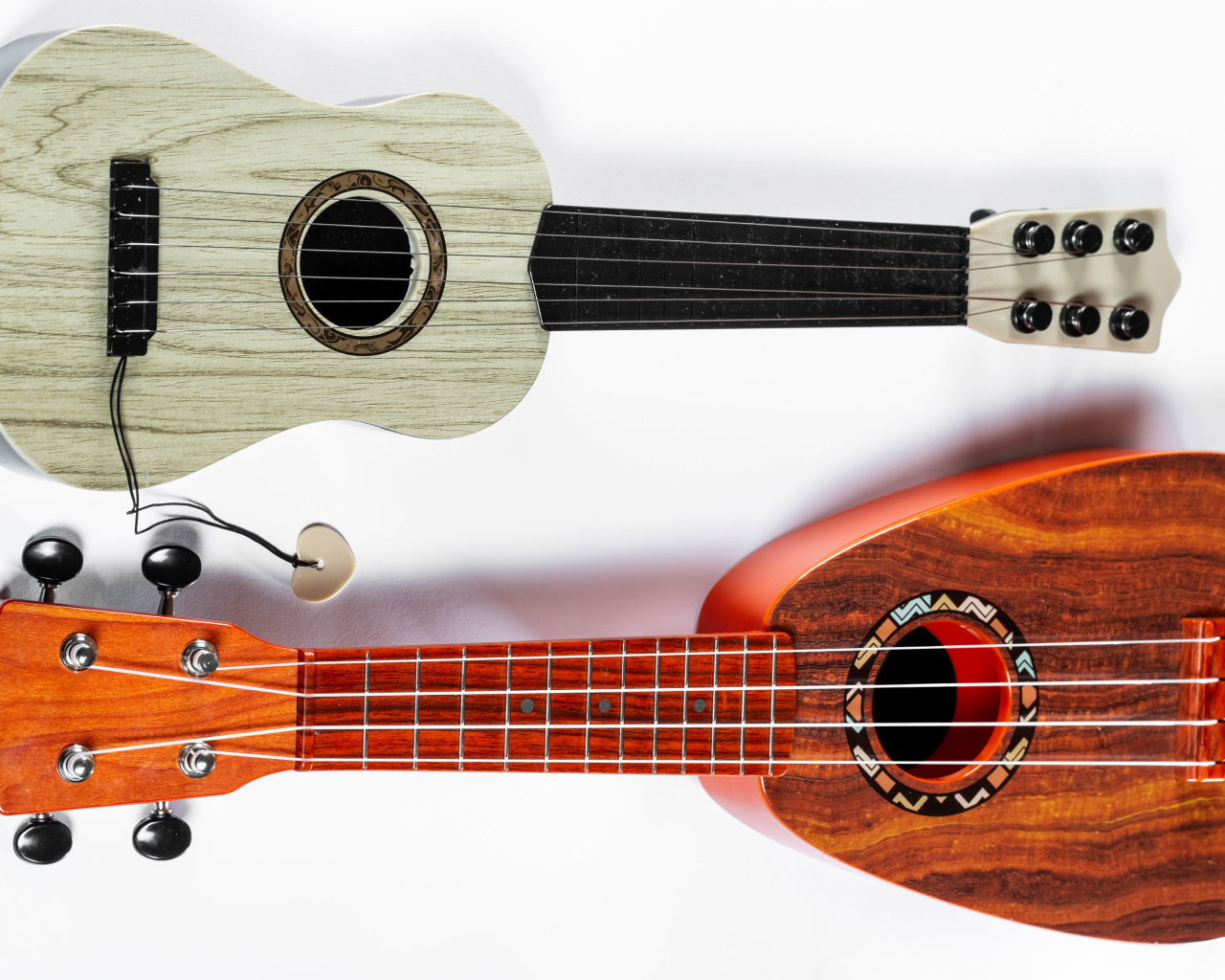 Две маленькие гитары укулеле на белом фоне