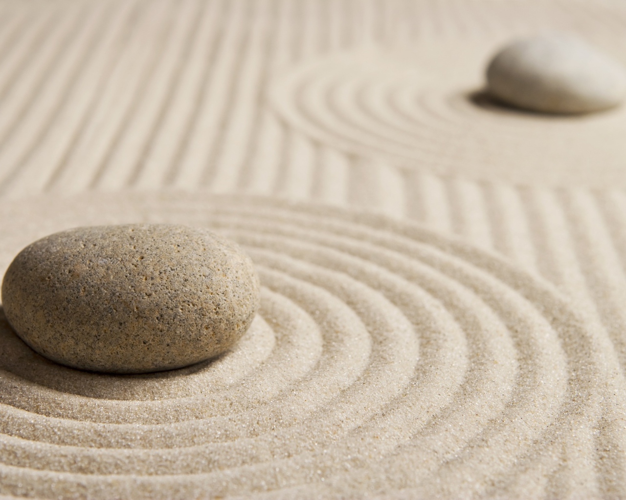 Большой серый камень на песке с кругами 