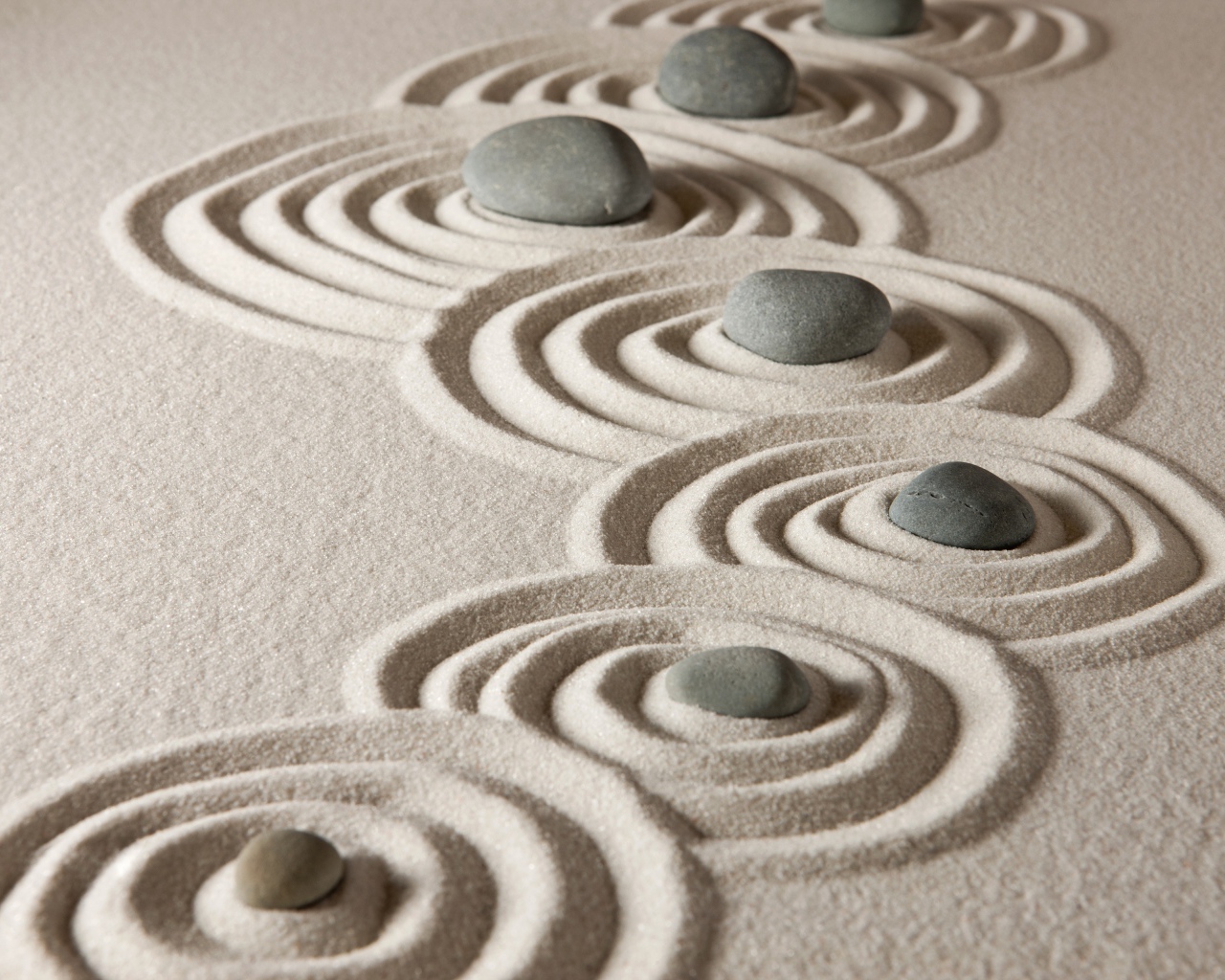 Маленькие серые камни с кругами на песке 