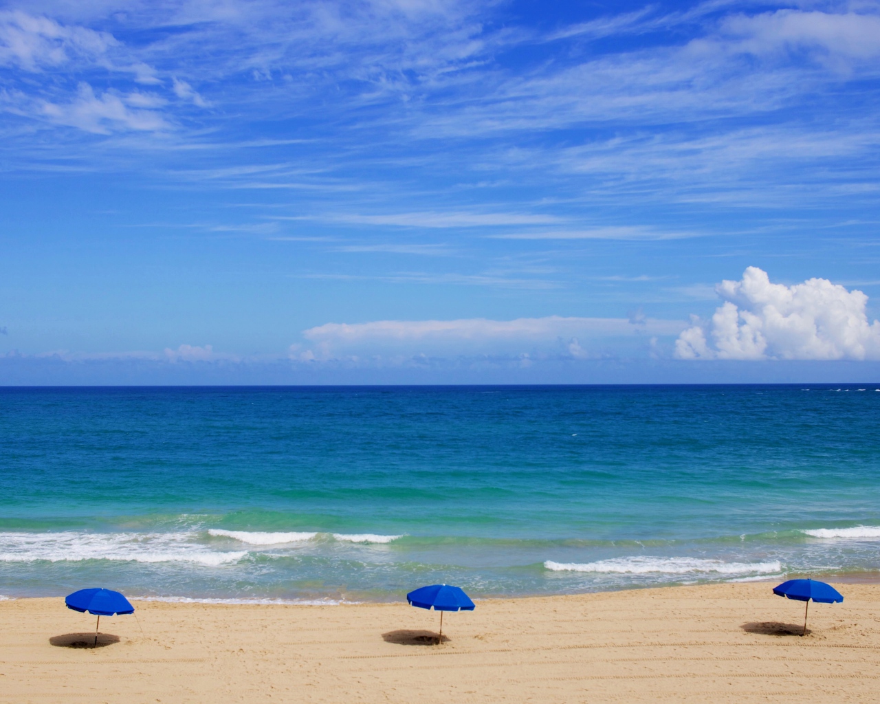 Зонтики на пляже у океана под голубым небом летом