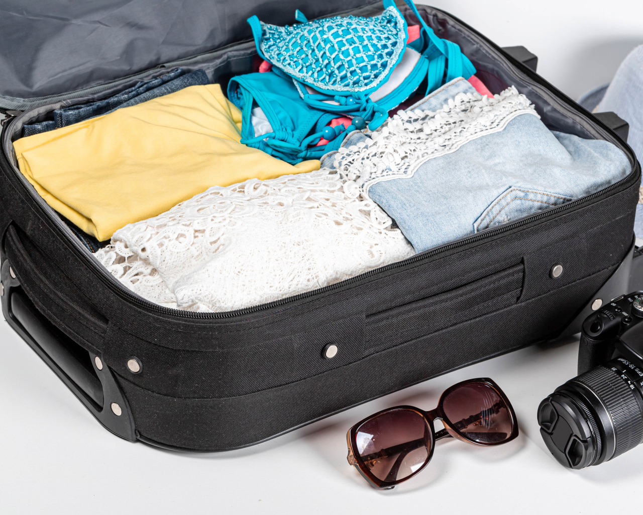 Чемодан с вещами для отпуска с фотоаппаратом и очками 