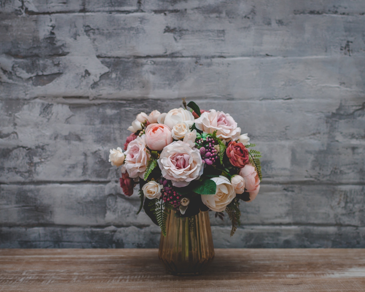 Розовый букет роз  стоит у серой стены 