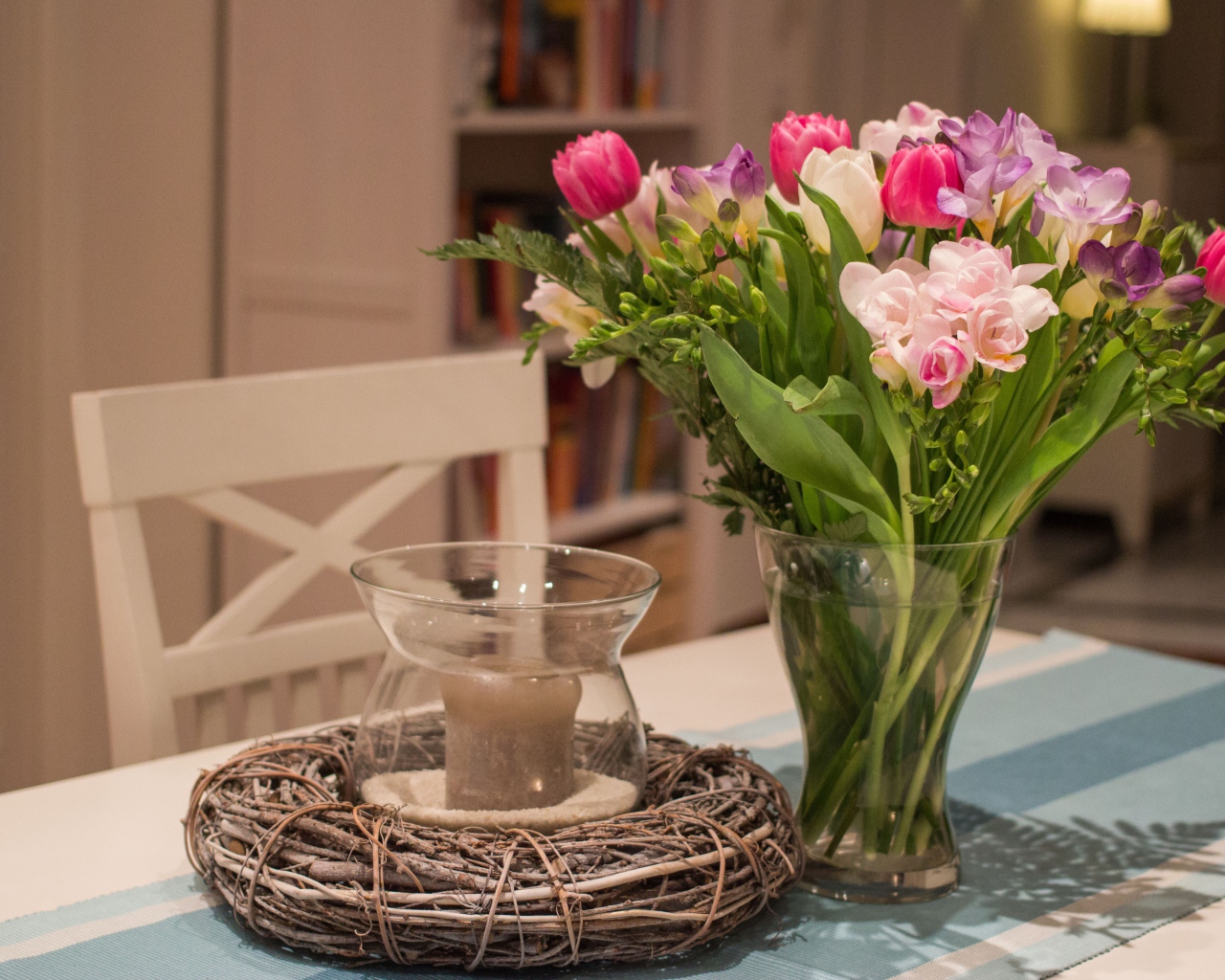 Красивый букет ярких цветов на столе со свечой