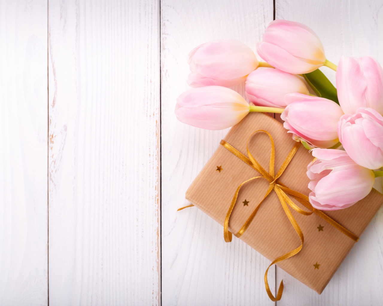 Букет нежных тюльпанов с подарком на деревянном столе