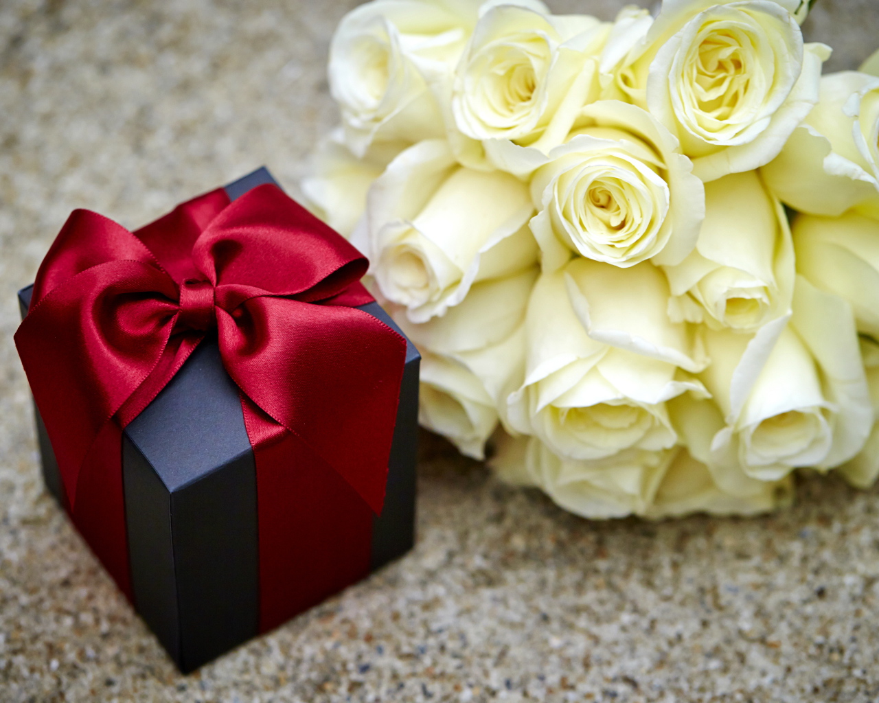 Букет белых роз с черным подарком на столе