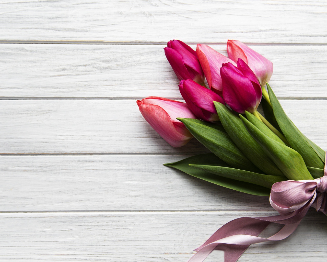 Весенний букет розовых тюльпанов с бантом на столе