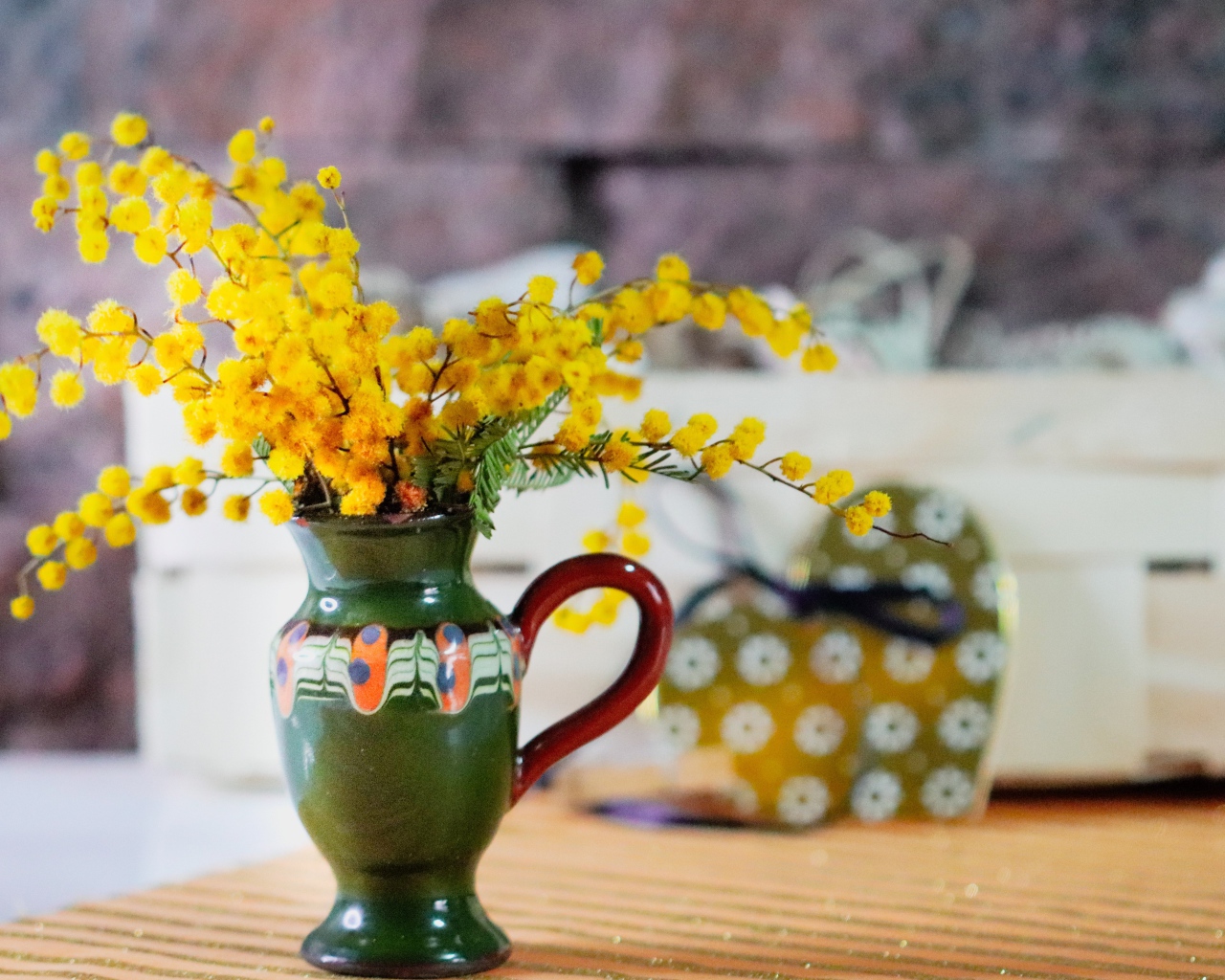 Желтые цветы мимозы в маленькой вазе на столе