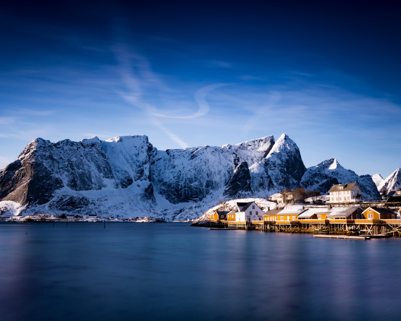 Красивый вид на дома у заснеженных гор под голубым небом 