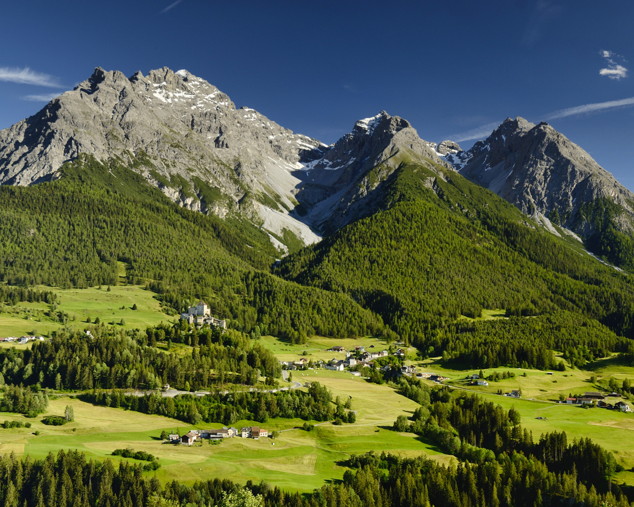 Высокие швейцарские Альпы покрыты зеленью под голубым небом 