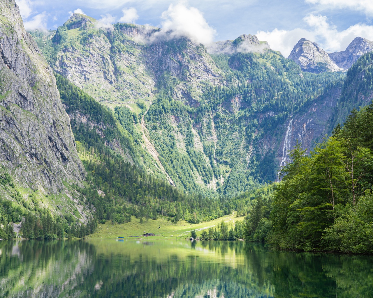 Высокие горы у озера с зелеными деревьями