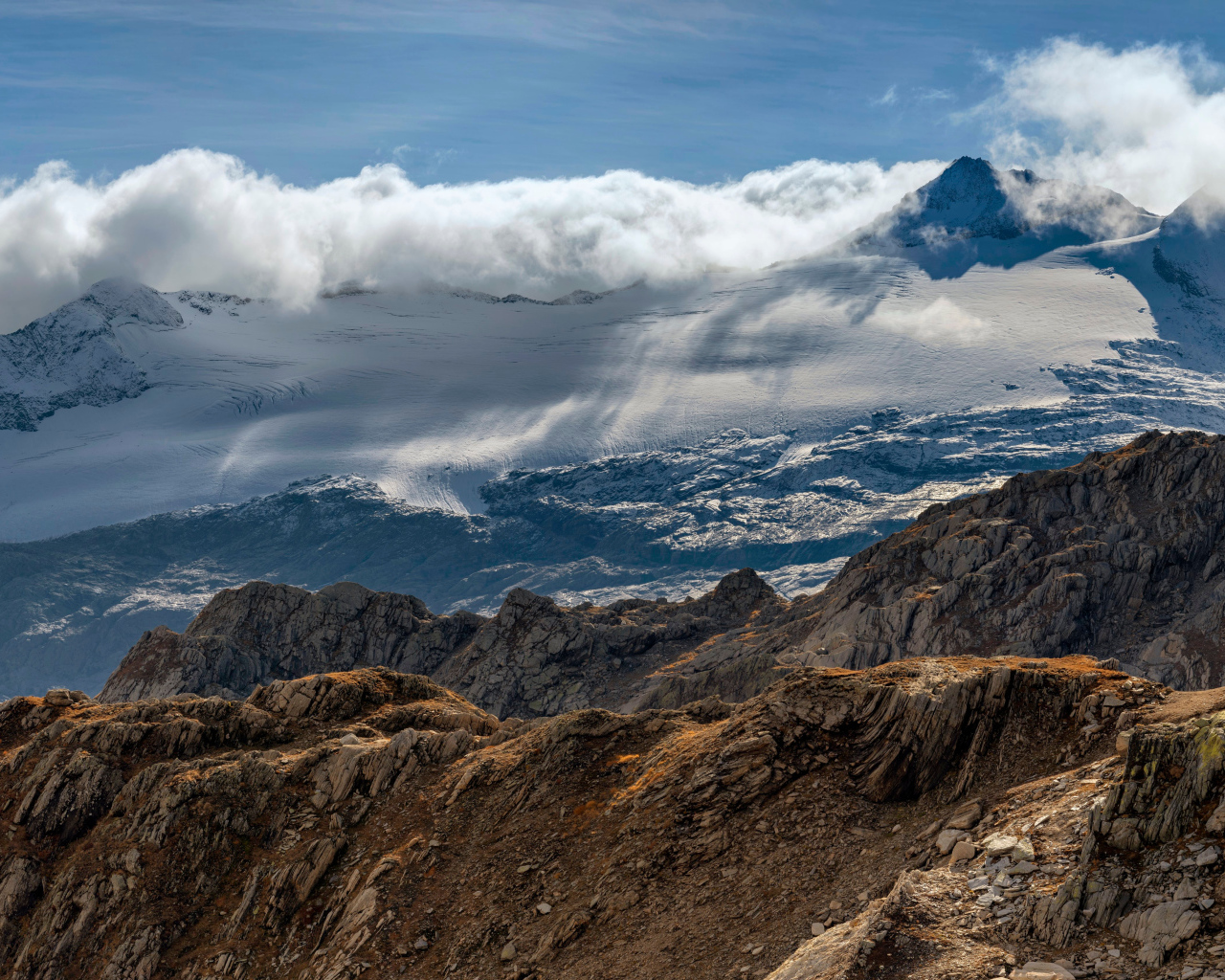 Густые белые облака над заснеженными Альпами