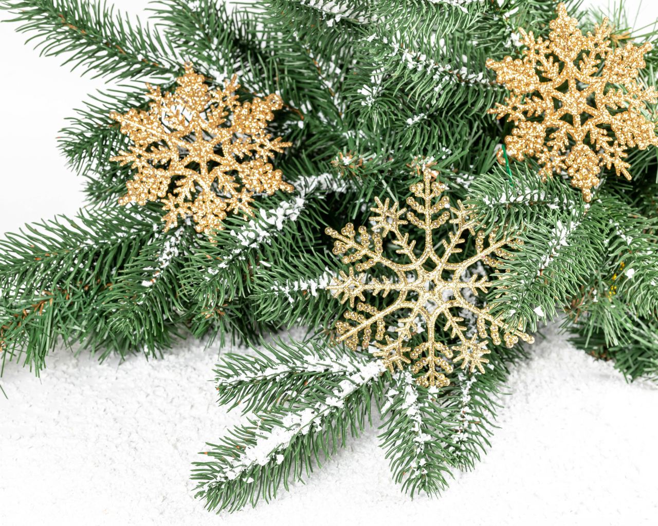Золотистые снежинки и еловые ветки на снегу