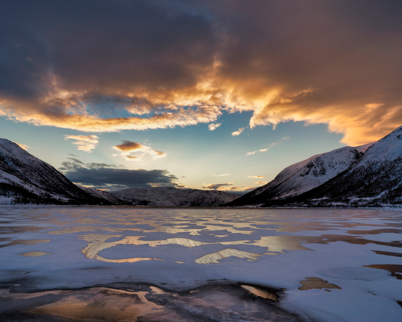 Покрытое льдом озеро у гор на закате солнца 