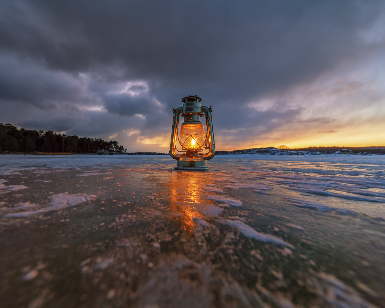 Керосиновая лампа стоит на покрытом льдом берегу