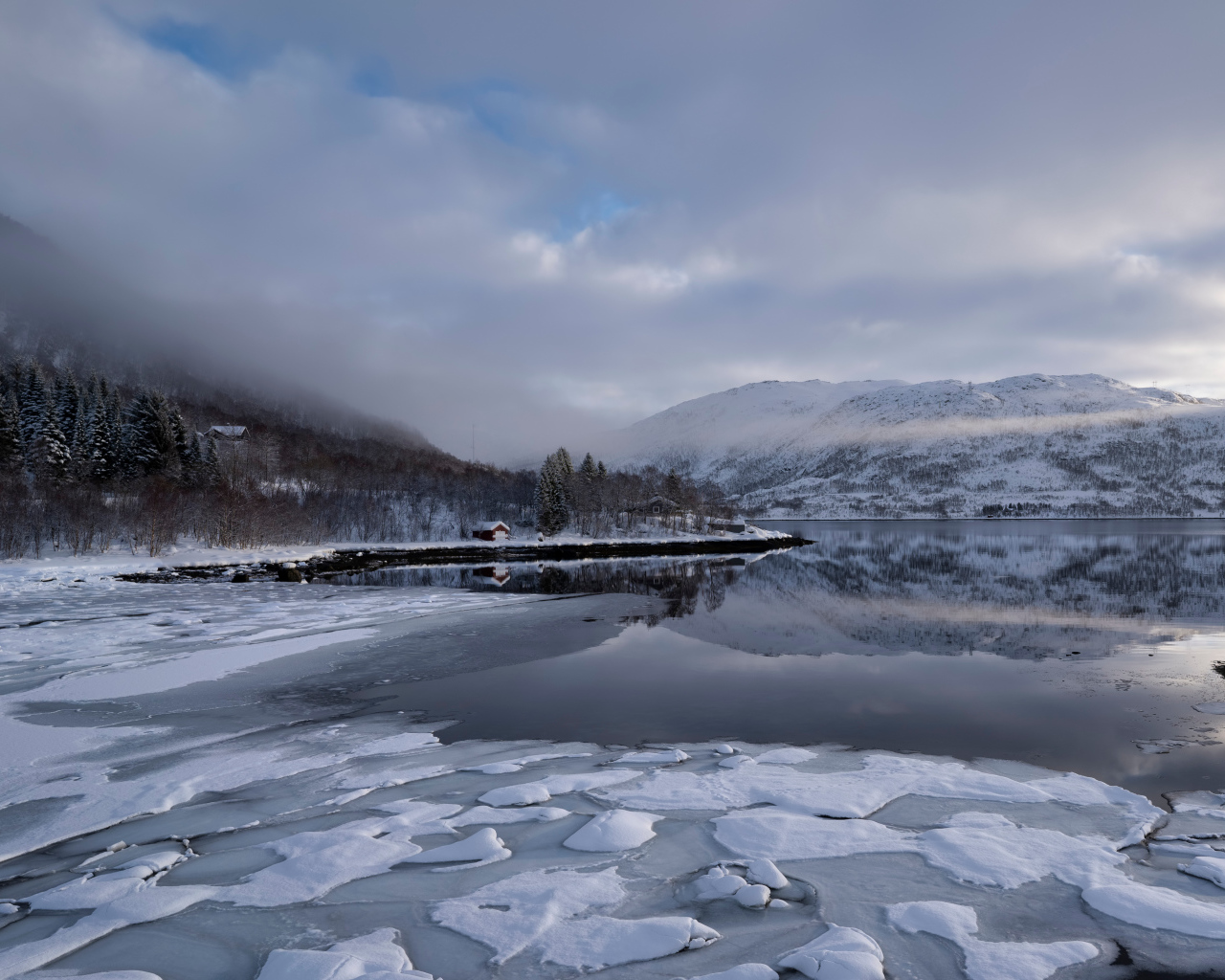 Покрытое льдом холодное озеро у гор в тумане