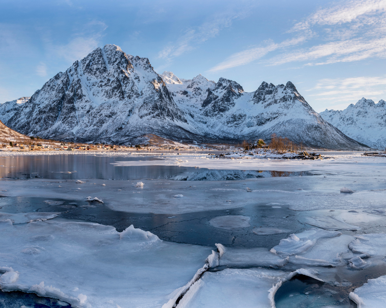 Покрытое льдом озеро у заснеженной горы