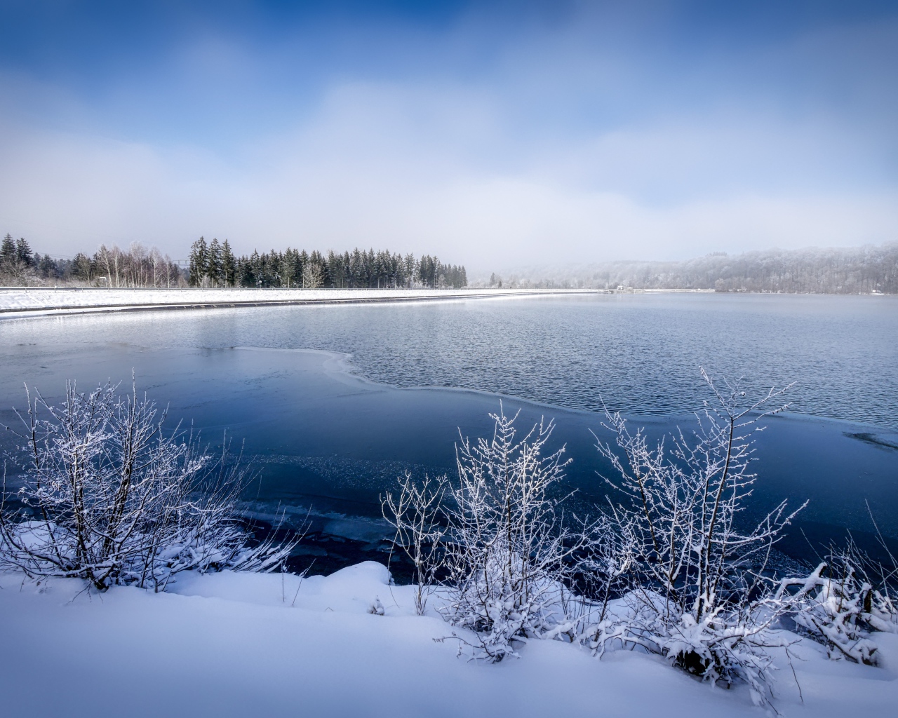 Покрытая льдом река  с заснеженными берегами зимой