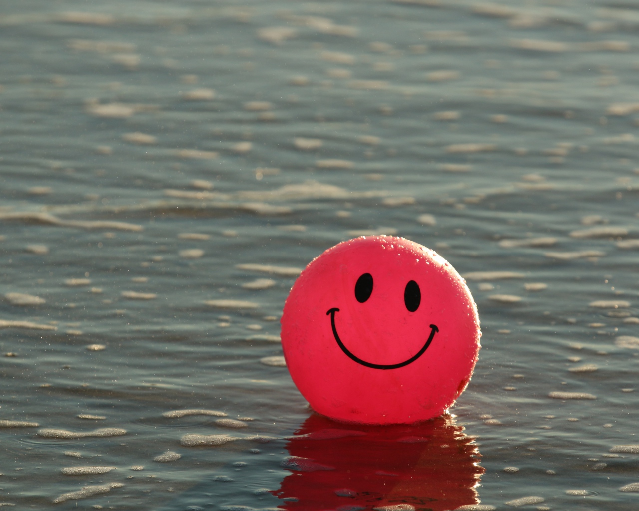 Красный мяч смайлик в воде 