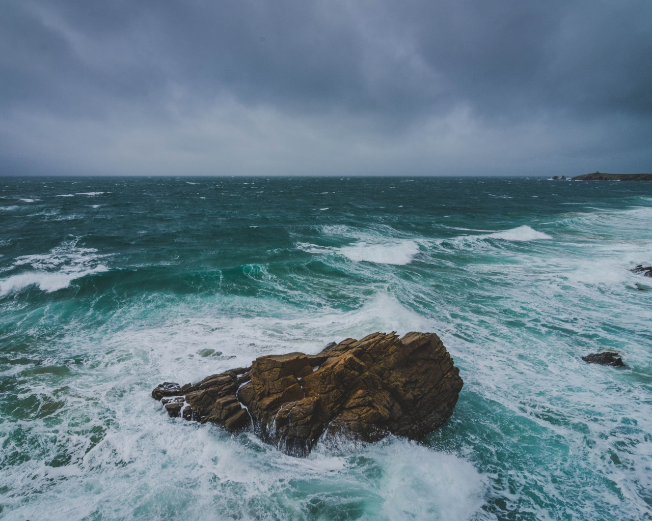 Большой камень омывают белые волны океана 