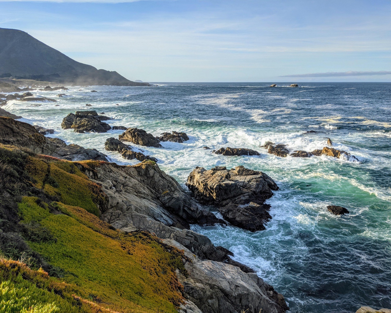 Голубая морская вода омывает камни на берегу 