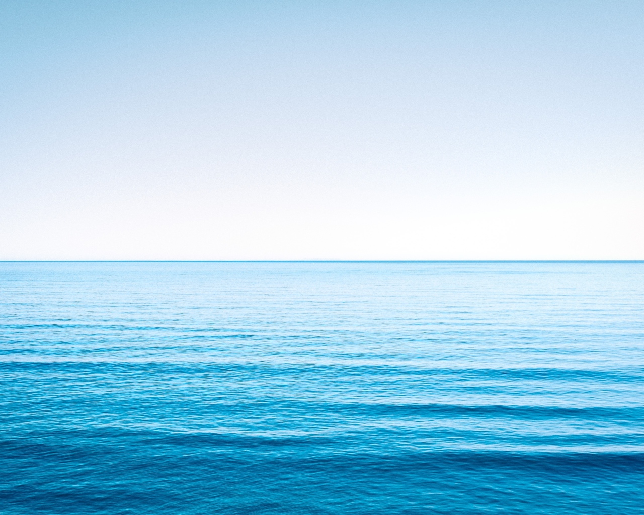 Спокойная голубая морская вода под голубым небом 