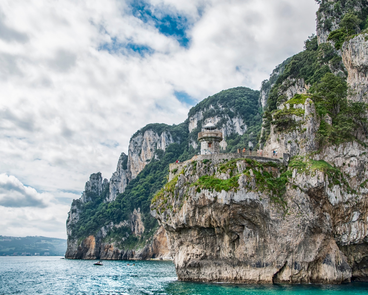 Высокие скалы у моря под белыми облаками 