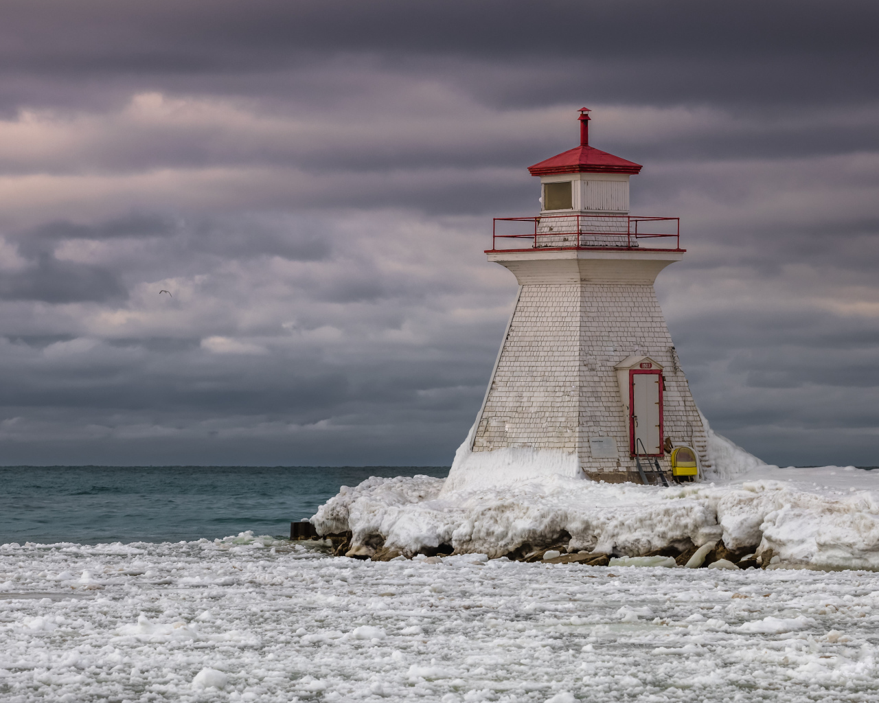 Маяк на покрытом льдом берегу у моря