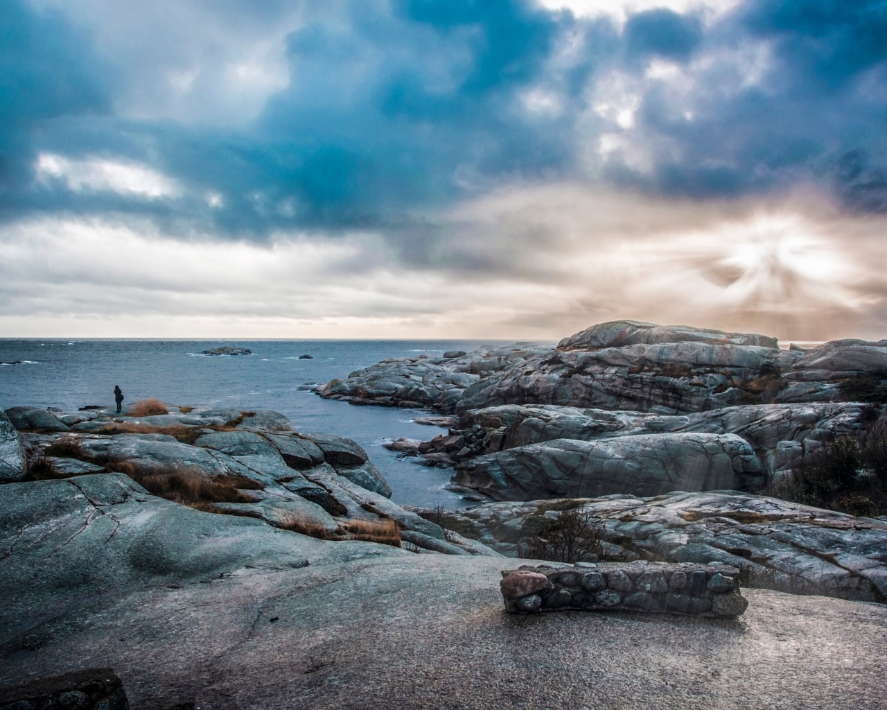 Каменный берег у тихого моря под черными облаками