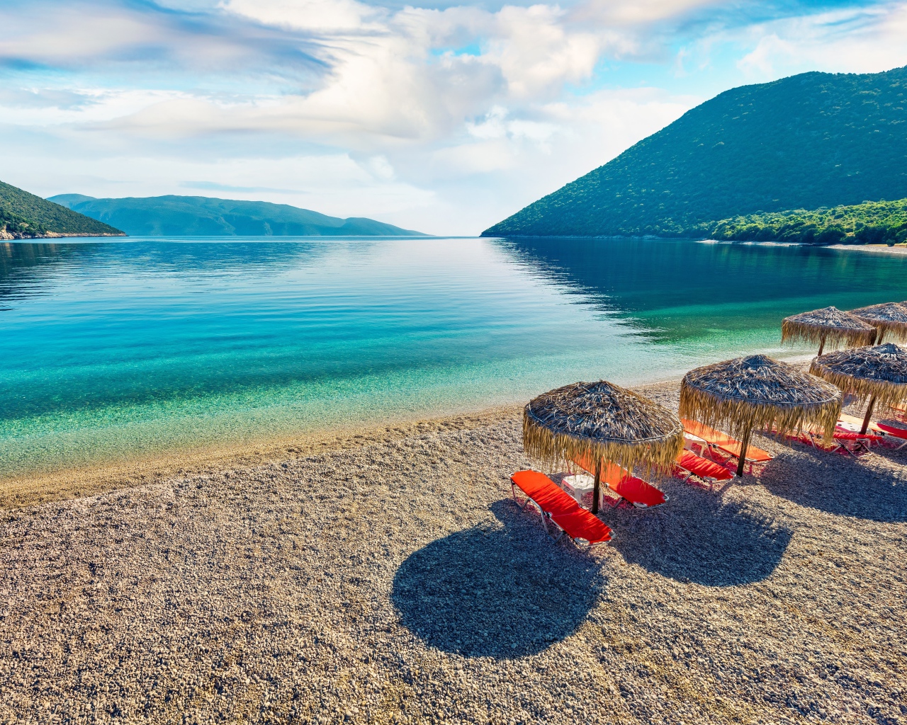 Шезлонги стоят на берегу озера у гор 