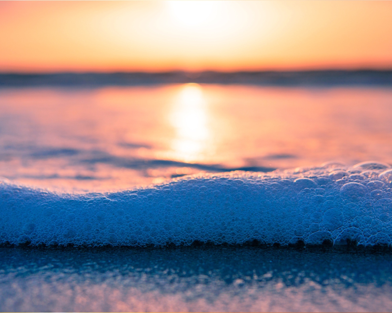 White sea foam with bubbles at sunset
