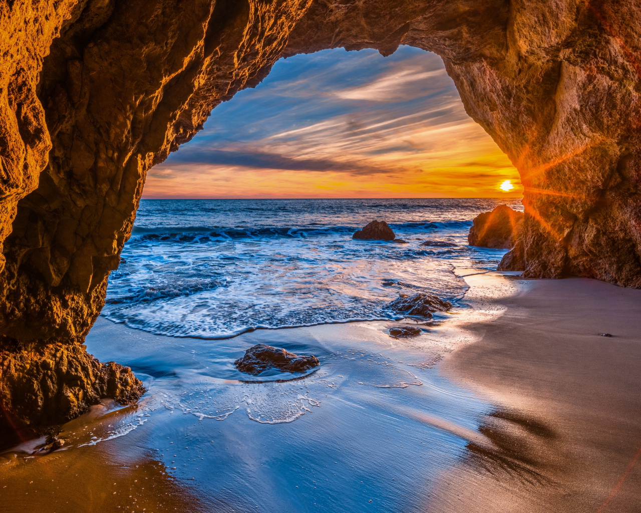 Закат солнца в каменной арке в море
