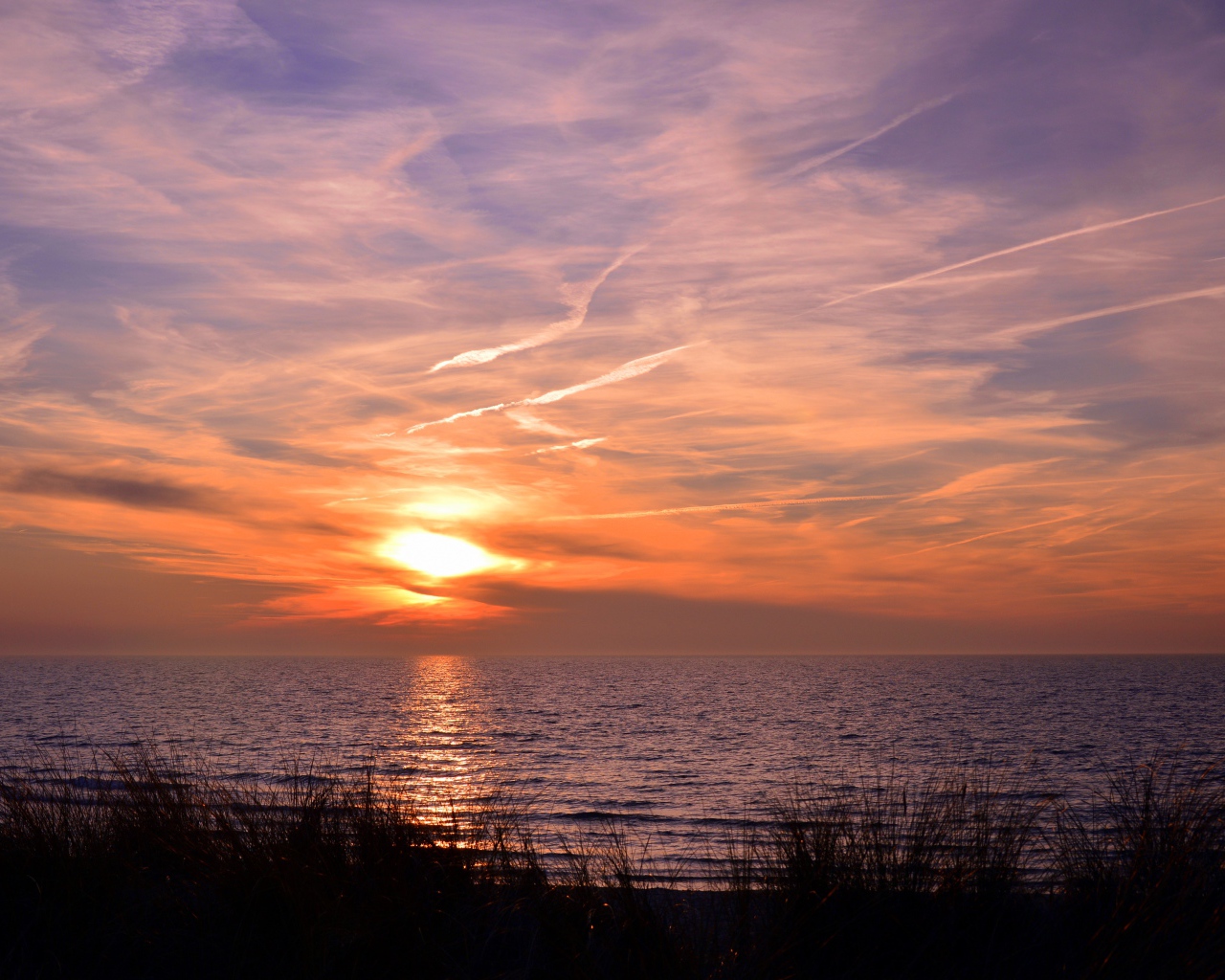 Закат солнца над спокойным озером летом
