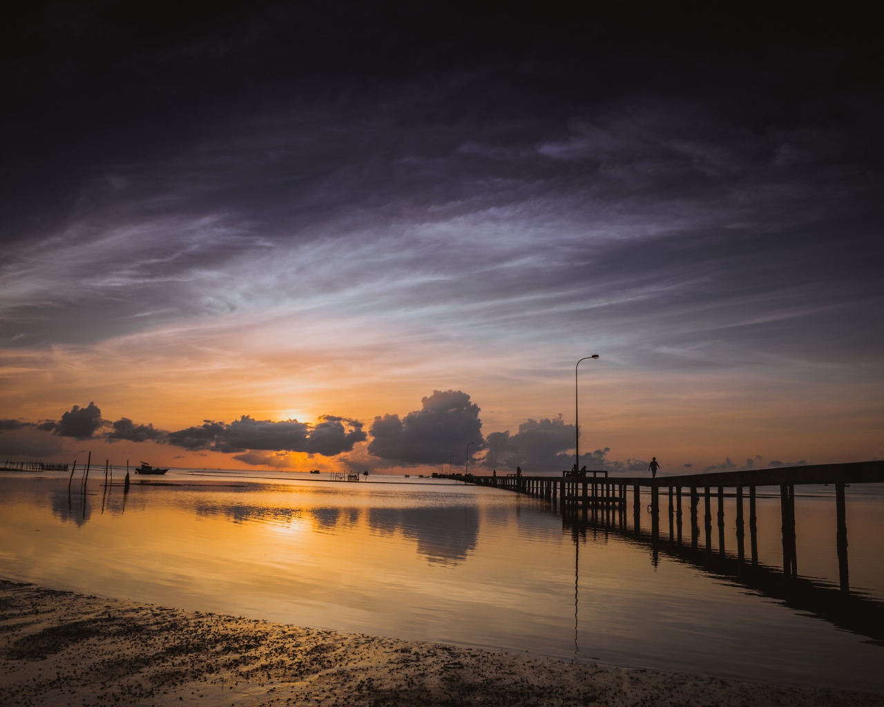 Деревянный мост на реке в лучах  солнца на закате