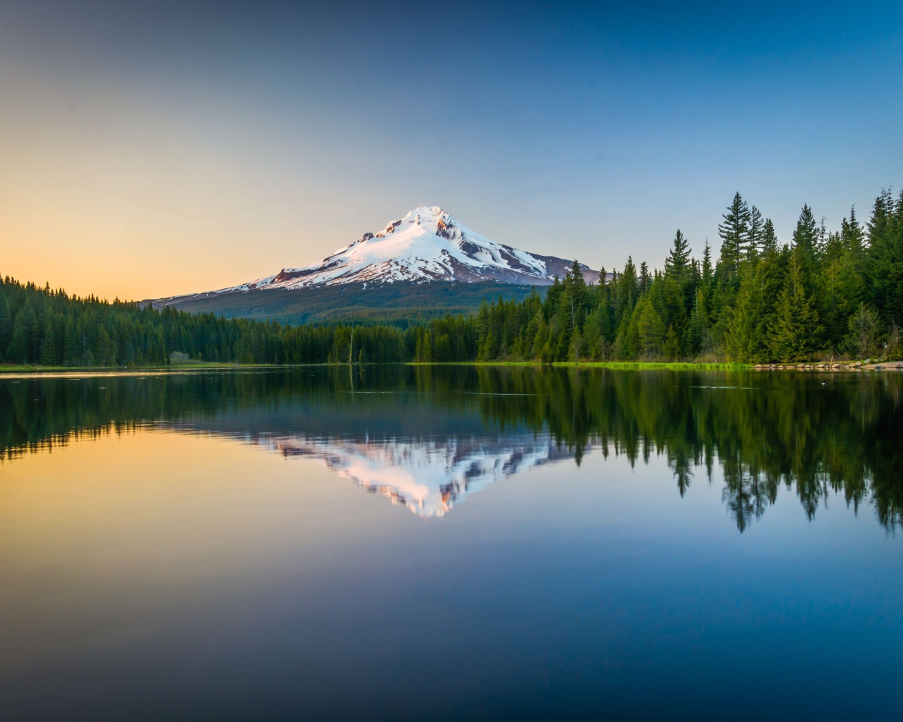 Заснеженная вершина вулкана отражается в холодной воде озера 